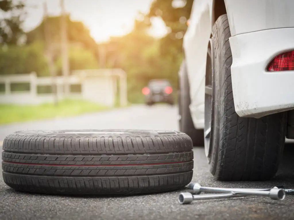 Neumático de repuesto a punto de subirse a un automóvil para reemplazar un pinchazo con una rosquilla.