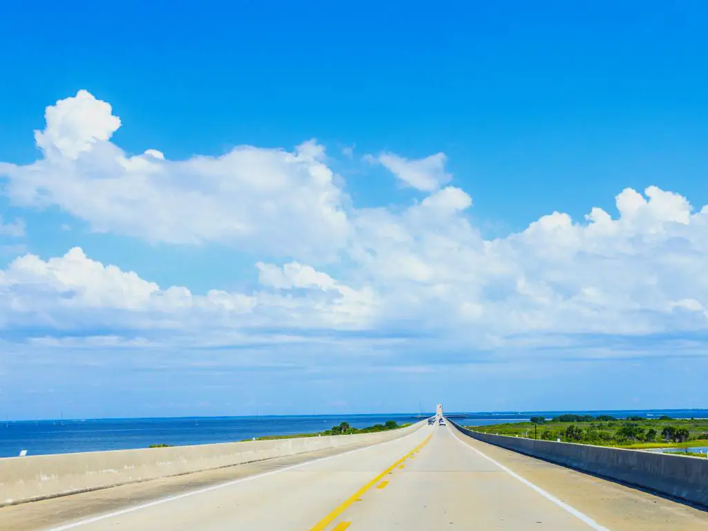Coches circulando por la carretera interestatal 193 en el puente Gordon Persons con una vista panorámica de Mobile Bay en un día soleado con una gruesa manta blanca de nubes de algodón estiradas